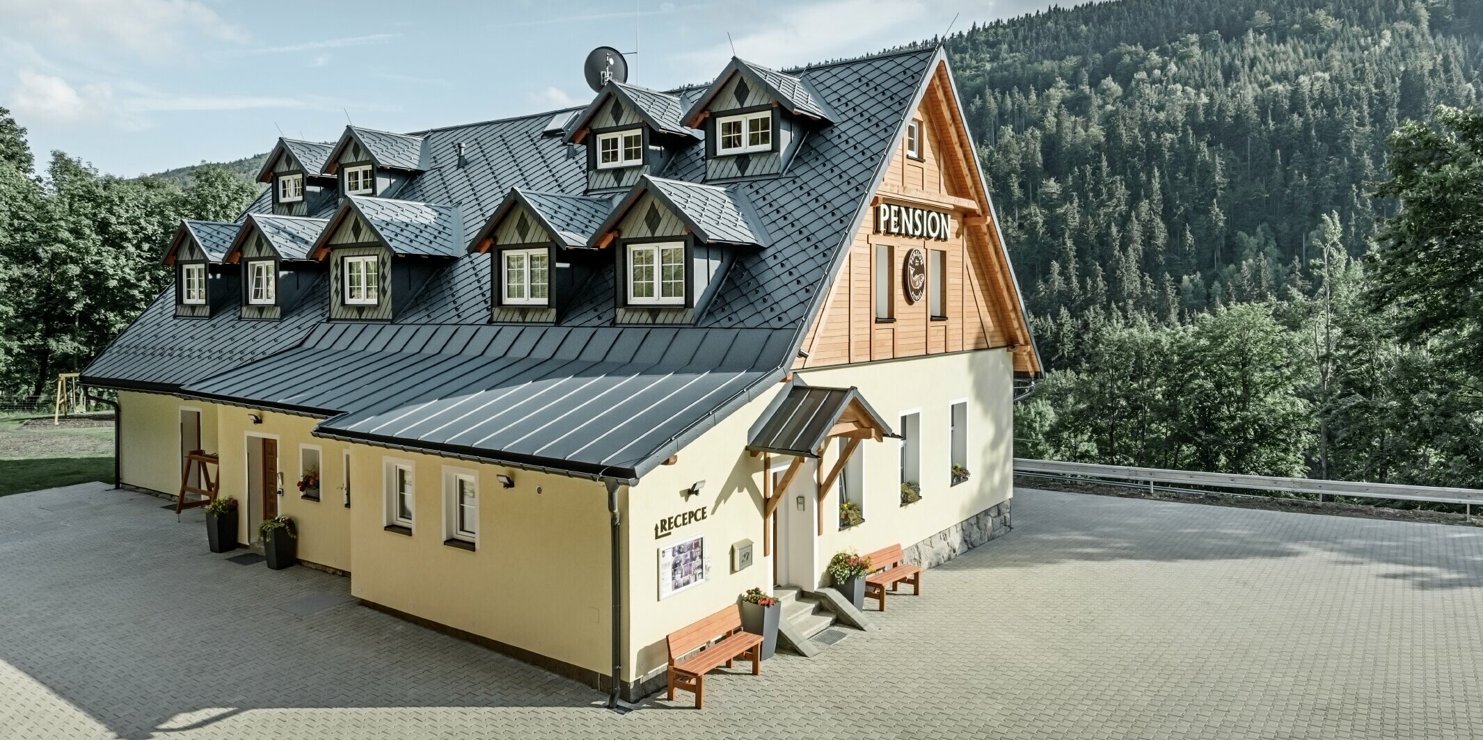 Pension in Tschechien mit Steildach und vielen Gauben eingedeckt mit Aluminiumdach von PREFA, schuppiges Rautendach mit Schneeschutz
