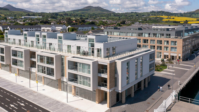 Marina Village Greystones in Wicklow, Irland – Weitwinkelaufnahme einer modernen Wohnsiedlung direkt am Wasser mit Blick auf den Yachthafen. Der Gebäudekomplex ist mit ca. 2.000 m² robustem PREFALZ in den Farben P.10 Prefaweiß und P.10 Hellgrau verkleidet. Die elegante Architektur umfasst große Glasfronten, geräumige Balkone und eine ästhetische Fassadengestaltung. Umgeben von einer malerischen Landschaft und hochwertigem Blech von PREFA bietet die Siedlung dauerhaften Schutz und zeitlose Ästhetik für exklusives Wohnen am Meer.