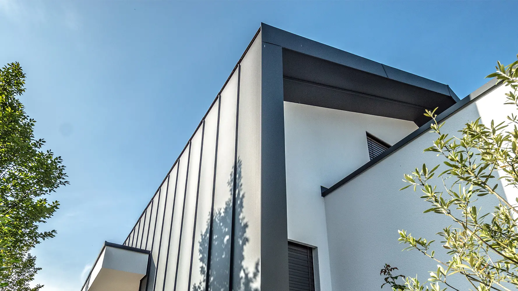Modernes Einfamilienhaus mit weißer Putzfassade und Stehfalzdach und -fassade mit Prefalz von PREFA in anthrazit.