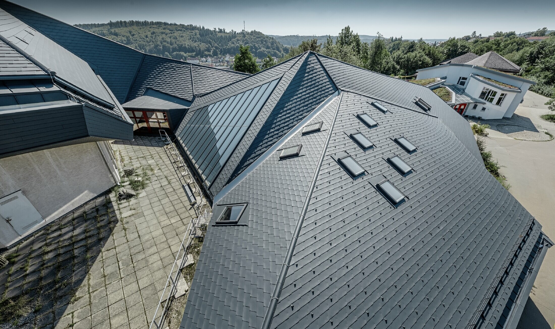 Waldorfschule in Heidenheim mit neu saniertem Dach, die große Dachfläche mit vielen Verwinkelungen und Dachneigungen wurde mit der PREFA Dachschindel in anthrazit eingedeckt