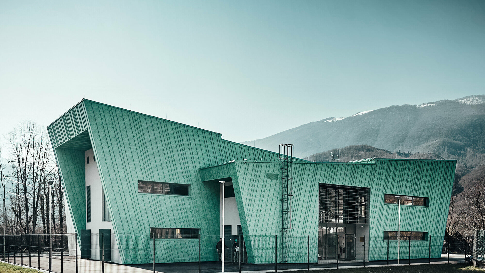 Seitliche Ansicht auf das Umspannwerk RTP Kobarid, entworfen von Damjan Holc von IBE d. d., das sich sanft in die Landschaft einfügt.