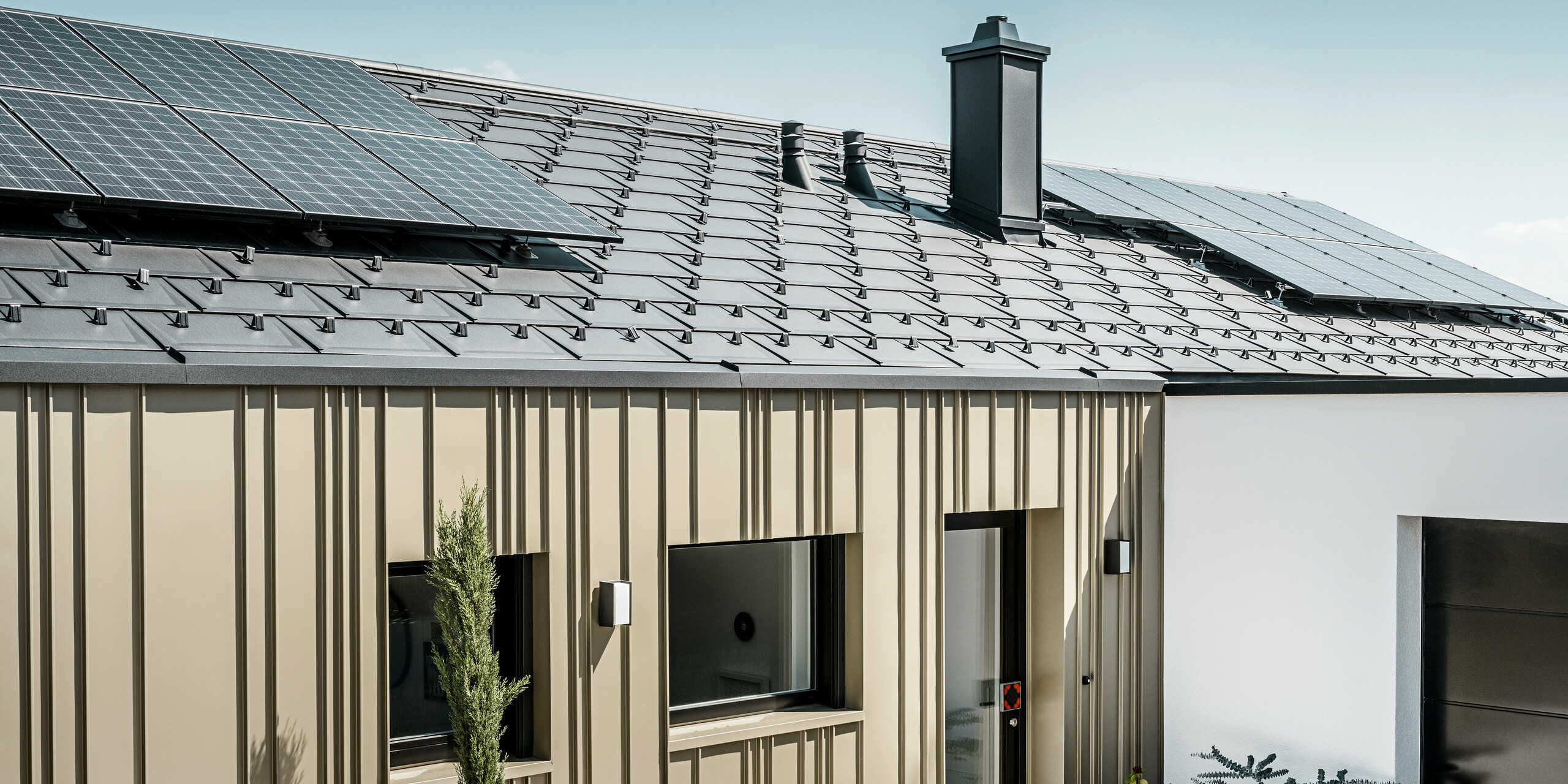 Ein Neubau in Bad Münstereifel wurde eingedeckt mit der PREFA Dachplatte R.16 in anthrazit. Auf dem Dach befindet sich eine Photovoltaik-Anlage. Die Winkelfalzfassade besteht aus Falzonal in lichtbronze.