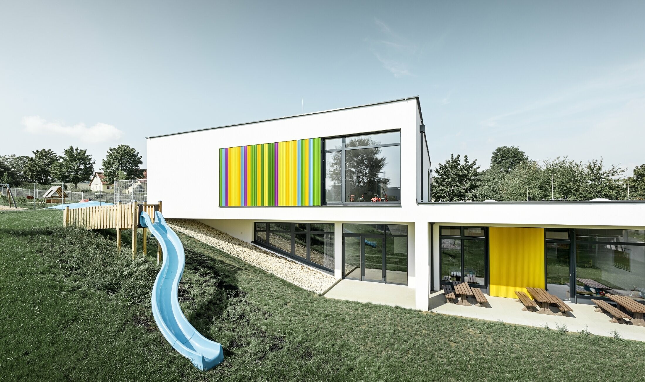 Rückansicht des Kindergarten in Hargelsberg mit buntem PREFA Zackenprofil in den Farben Gelb, Grün, Lila und Blau
