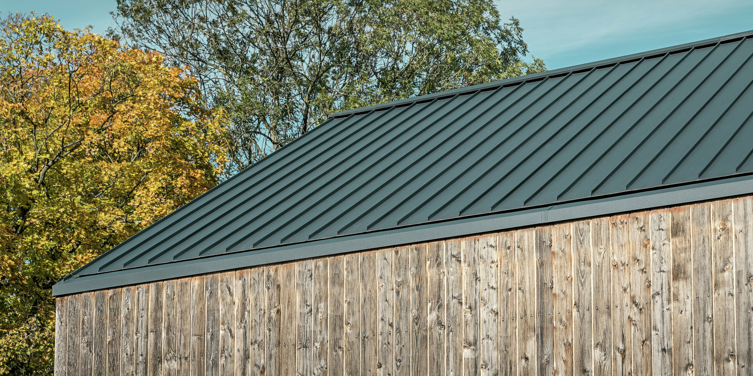 Modernes Satteldach mit PREFALZ Doppelstehfalz in P.10 Anthrazit. Das hochwertige Blechdach auf einem Wohnhaus mit der Fassade aus naturbelassenem Zedernholz schafft eine eindrucksvolle Optik. Das PREFA Dach ist langlebig, wetterbeständig und ästhetisch.