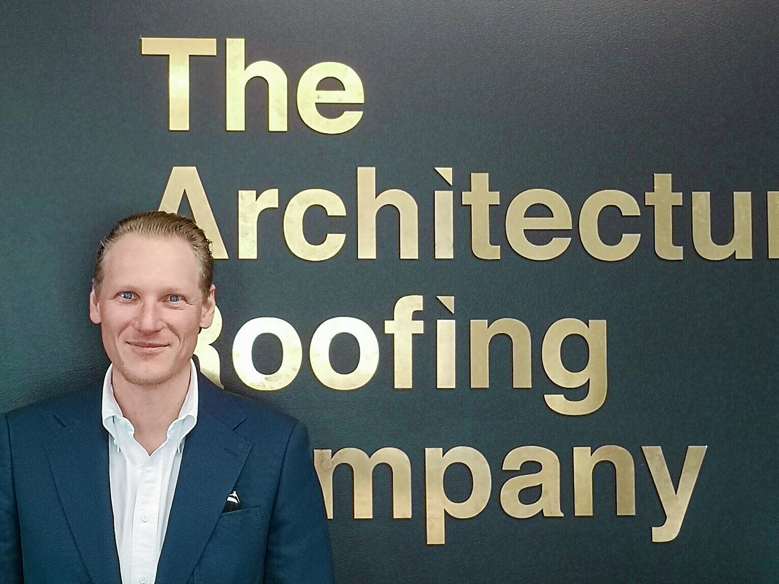 Portrait des Verarbeiters Johan Vogl, im Hintergrund der Firmenname "The Architectural Roofing Company".