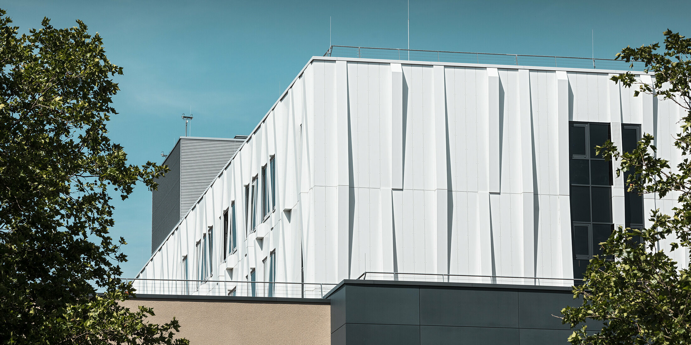 Blick aus der Ferne auf die reinweiße Aluminiumfassade des Universitätsklinikums St. Pölten. Die Aluminiumverbundplatten als Kassettenfassade machen das Gebäude zu einem Blickfang.