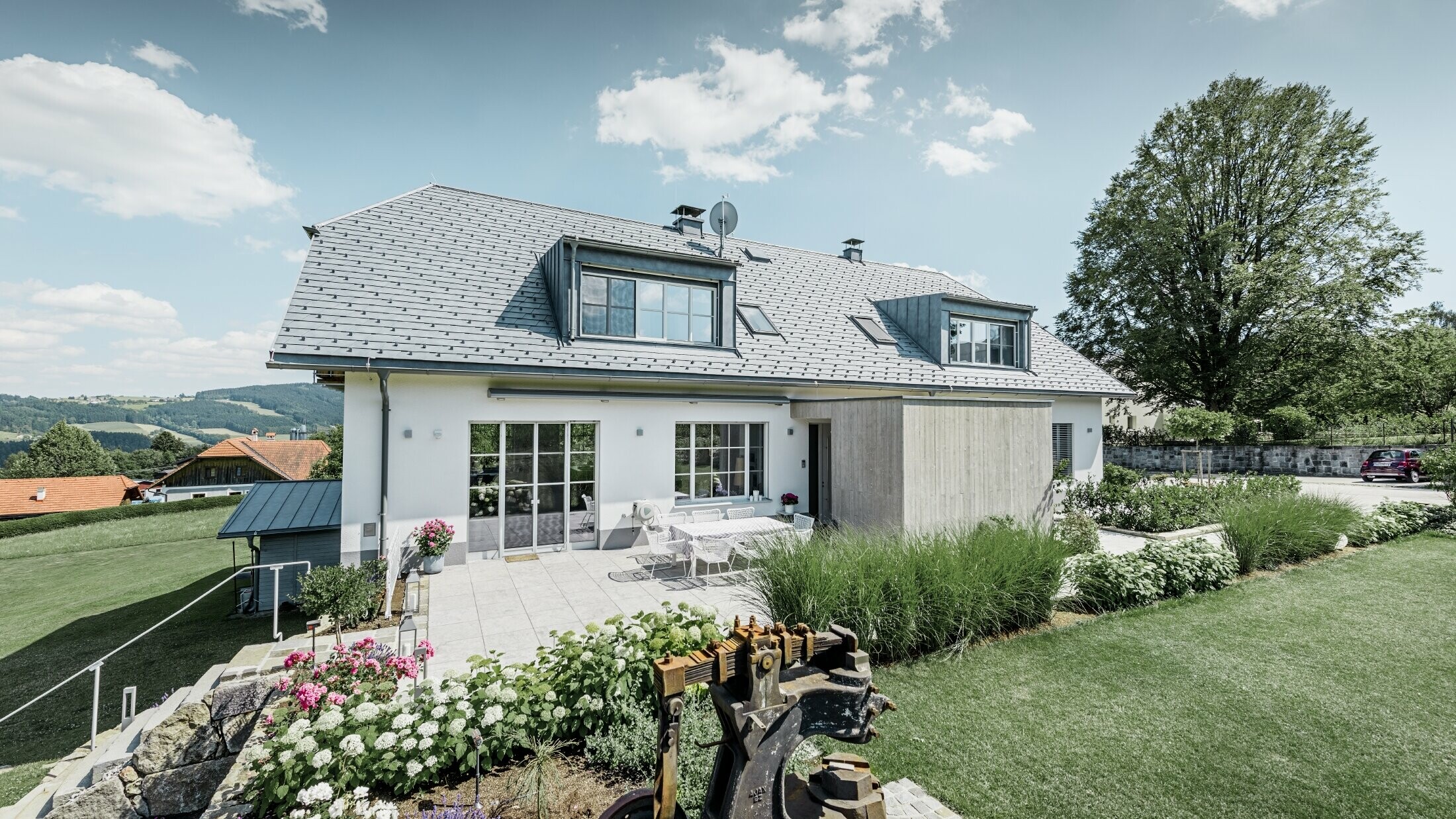 Klassisches Einfamilienhaus mit Krüppelwalmdach; Das Haus mit Dachsanierung mit der PREFA Dachschindel in Steingrau mit schön angelegtem Garten und großzügiger Terrasse.