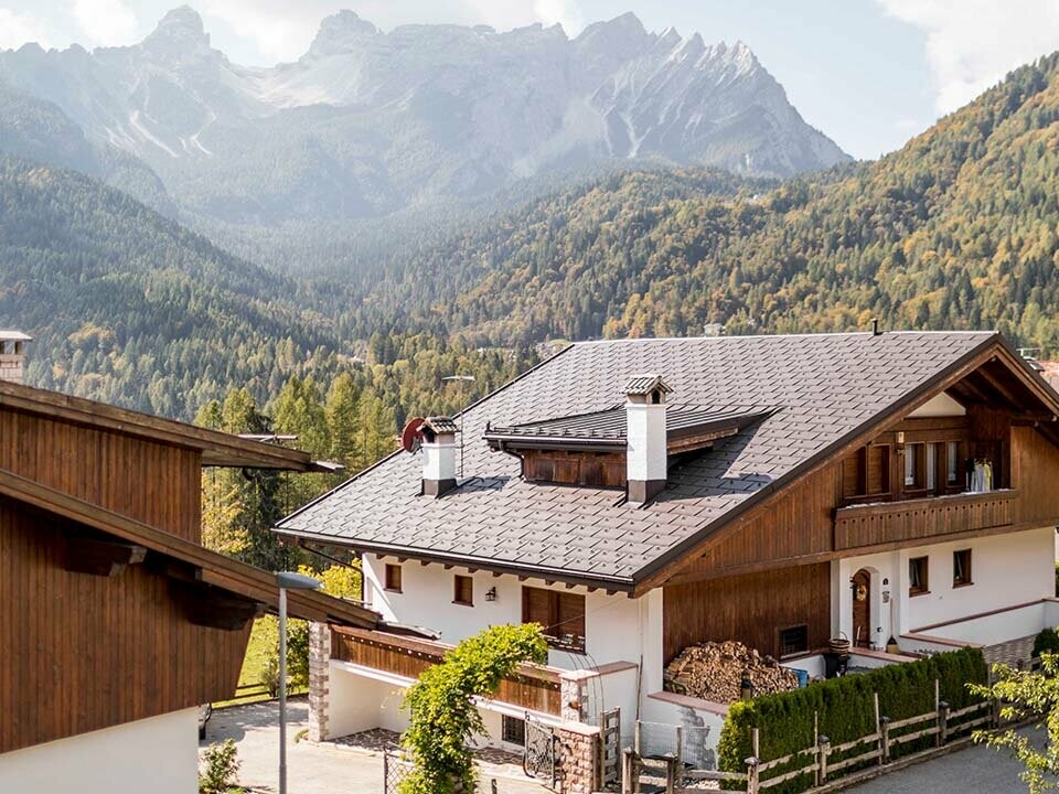 Dieses Wohnhaus in den Dolomiten wurde mit PREFA Dachplatten R.16 in P.10 Nussbraun eingedeckt, das traditionelle Haus liegt inmitten der Berge in Italien