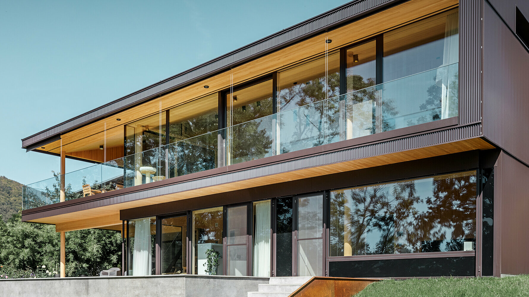 Neues Einfamilienhaus mit großen Glasflächen und brauner Aluminium Fassade