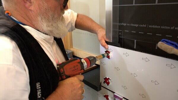 PREFA-Techniker Tom Weiß mittels Einhandfeder-Bohrvorrichtung ein Loch in die Verbundplatte.