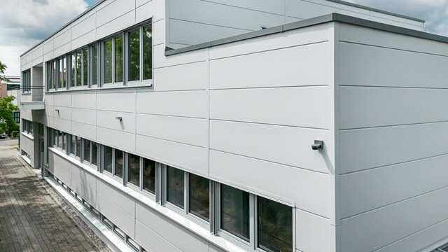 Großformatige PREFA Sidings umhüllen ein Firmengebäude in Oberschleißheim (Deutschland). Die extrabreiten Fassadenelemente aus Aluminium sind in der Farbe Prefaweiß gehalten.
