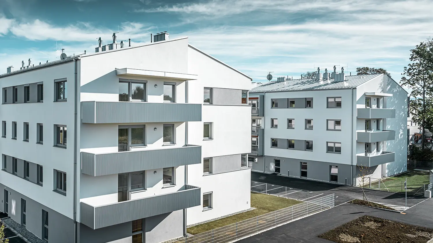 Moderne Wohnhausanlage mit weißer Fassade und Balkonen mit PREFA Zackenprofil in Silbermetallic