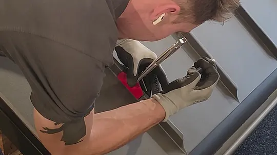 Ein Klempner arbeitet konzentriert an der Montage des PREFALZ Bleches und setzt ein Handwerkzeug ein, um das Material exakt zu bearbeiten.