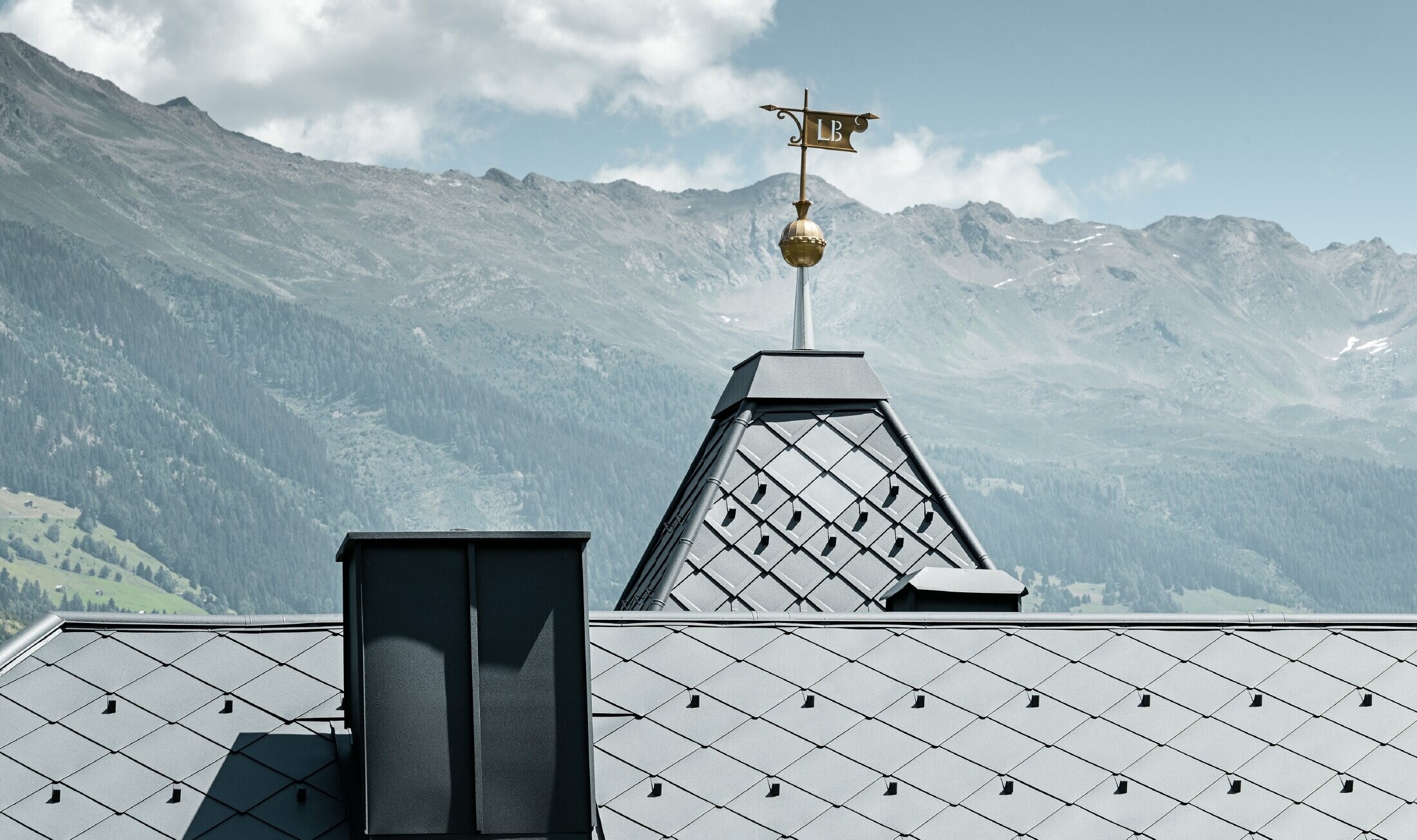 Felsenhaus mit Turm und einem Aluminiumdach in anthrazit mit einer Pizzeria im Erdgeschoss