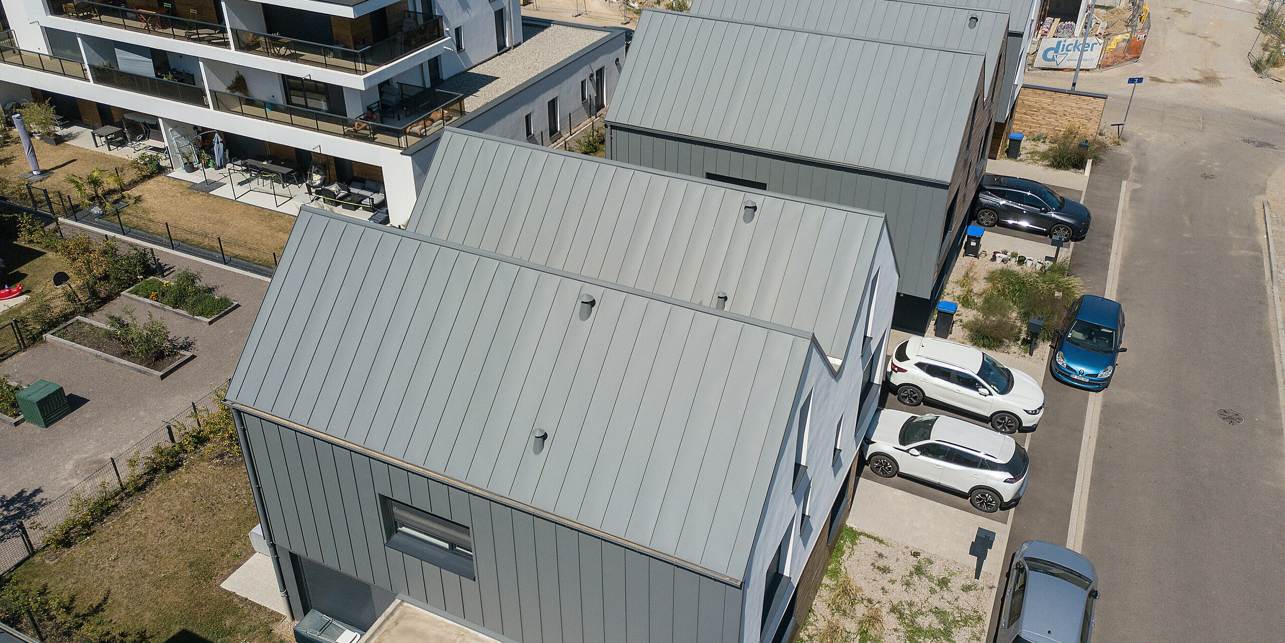 PREFALZ in Hellgrau zieht sich über die Fassaden und Satteldächer einer Reihenhaus-Siedlung in Mundolsheim. Die einheitlichen Gebäudehüllen aus Aluminium schaffen ein harmonisches Gesamtbild.