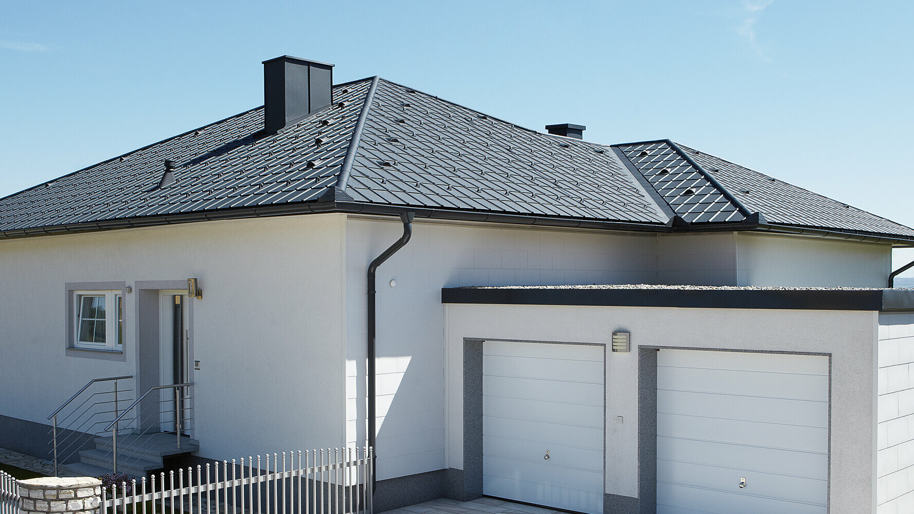 Sanierter Bungalow mit Walmdach und PREFA Dachplatte in Anthrazit eingedeckt. Daneben steht eine Doppelgarage.