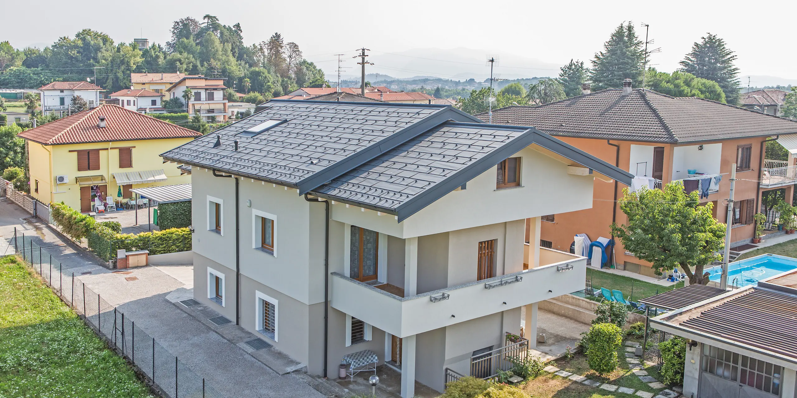 Modernes Einfamilienhaus in Beregazzo, Italien, mit markantem Satteldach aus PREFA Dachpaneelen FX.12 in P.10 Anthrazit. Die unregelmäßig gekanteten Aluminium-Paneele erzeugen ein lebendiges Licht- und Schattenspiel und setzen einen starken architektonischen Akzent. Das langlebige PREFA Aluminiumdach verbindet zeitgemäßes Design mit hoher Widerstandsfähigkeit und zuverlässigem Schutz vor Witterungseinflüssen.