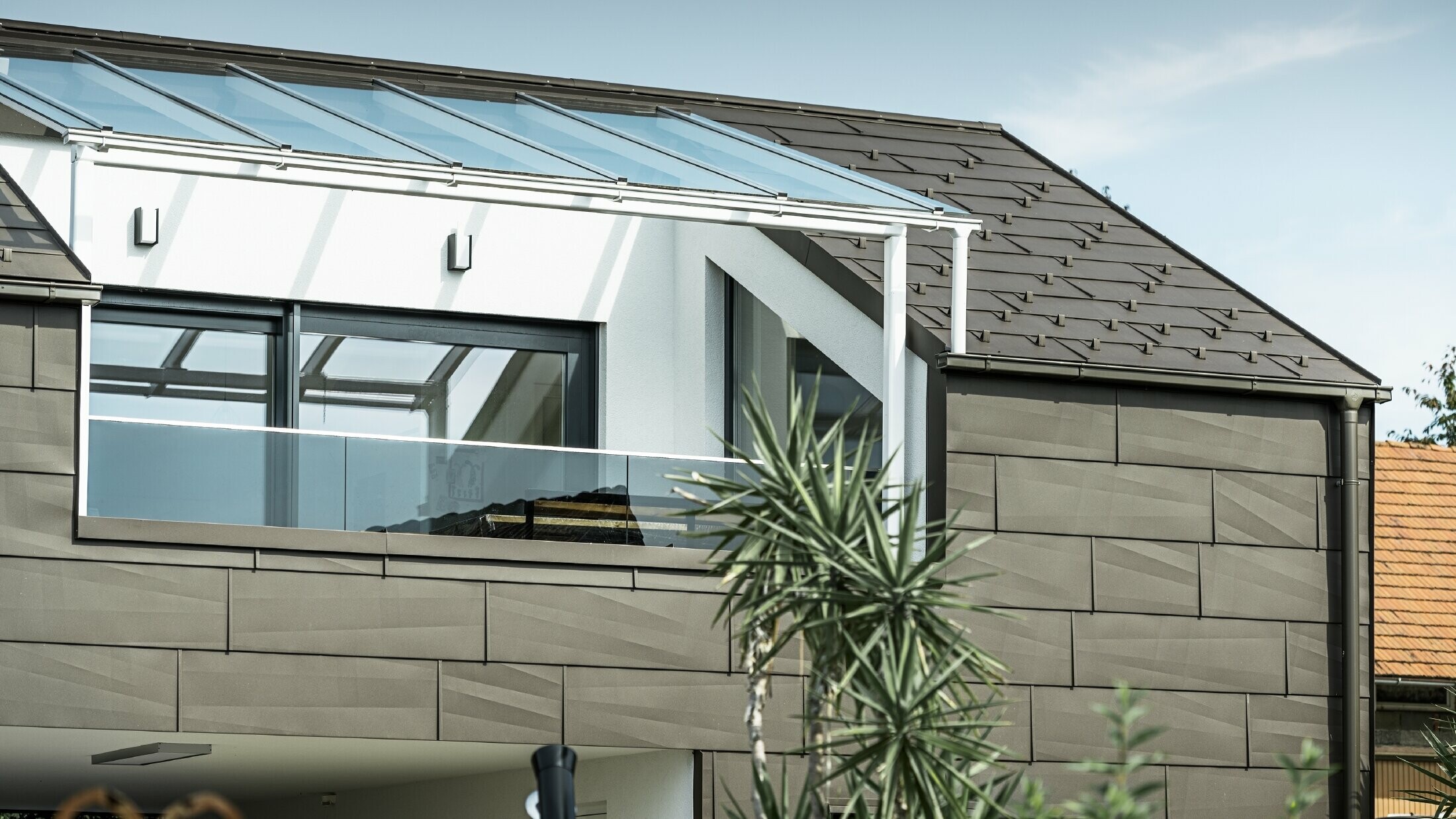 Zubau mit Dachterrasse mit dem PREFA Komplettsystem verkleidet, am Dach und an der Fassade wurden das PREFA Dach- und Fassadenpaneel FX.12 verwendet. Außerdem kommt die PREFA Kastenrinne mit dem PREFA Ablaufrohr und dem umfangreichen Zubehör in Braun als Dachentwässerung zum Einsatz.