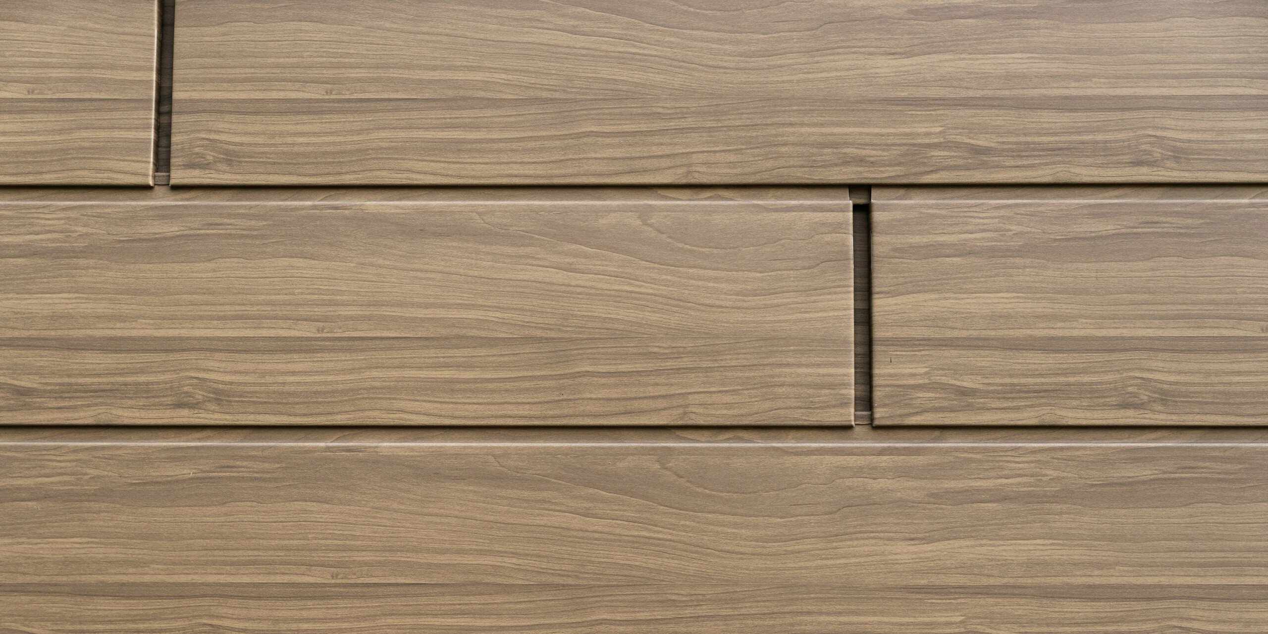 Detailansicht der wallnussbraunen PREFA Sidings mit authentischer Holzoptik. Die langlebigen Aluminium-Fassadenpaneele verbinden natürliche Ästhetik mit Wartungsfreiheit und Witterungsbeständigkeit.