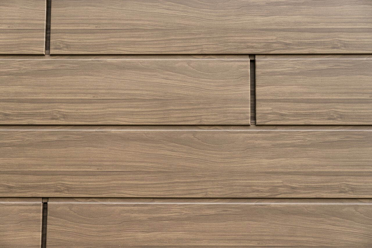 Detailansicht der wallnussbraunen PREFA Sidings mit authentischer Holzoptik. Die langlebigen Aluminium-Fassadenpaneele verbinden natürliche Ästhetik mit Wartungsfreiheit und Witterungsbeständigkeit.