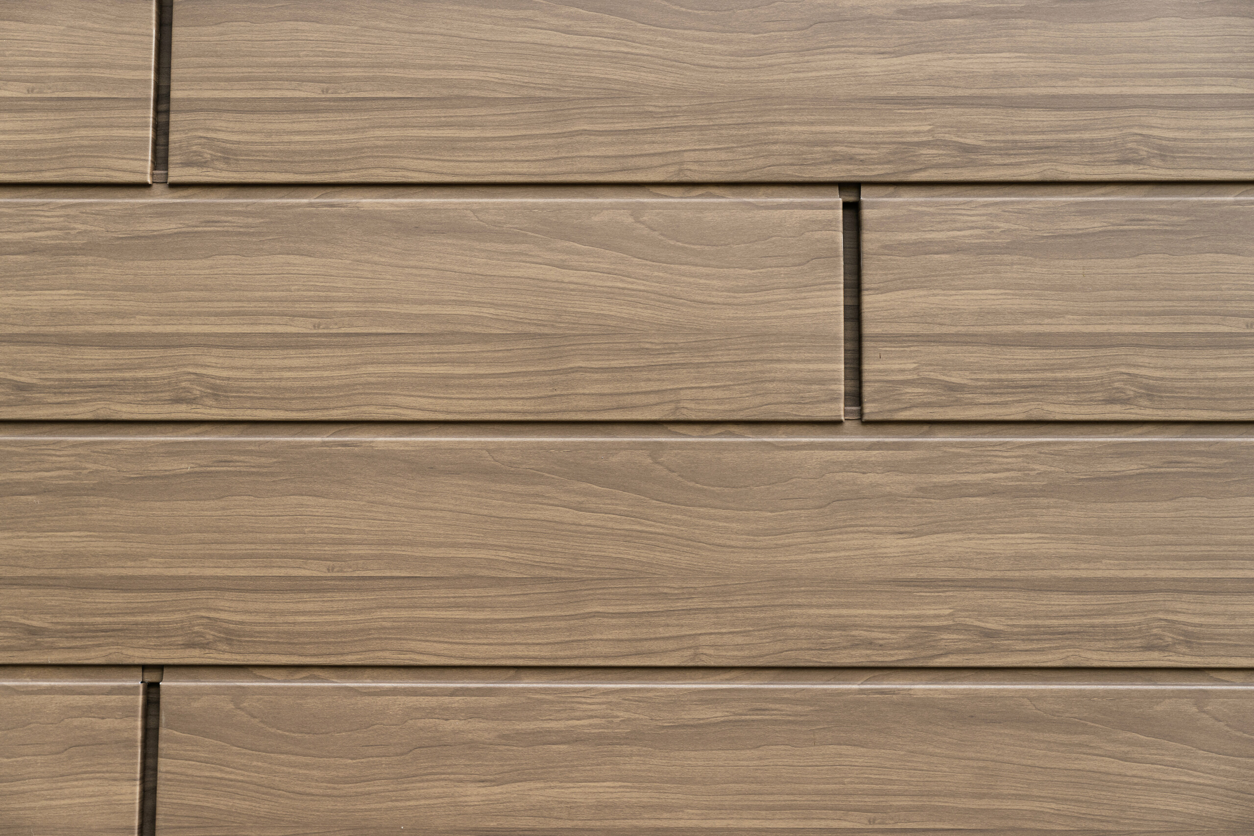 Detailansicht der wallnussbraunen PREFA Sidings mit authentischer Holzoptik. Die langlebigen Aluminium-Fassadenpaneele verbinden natürliche Ästhetik mit Wartungsfreiheit und Witterungsbeständigkeit.