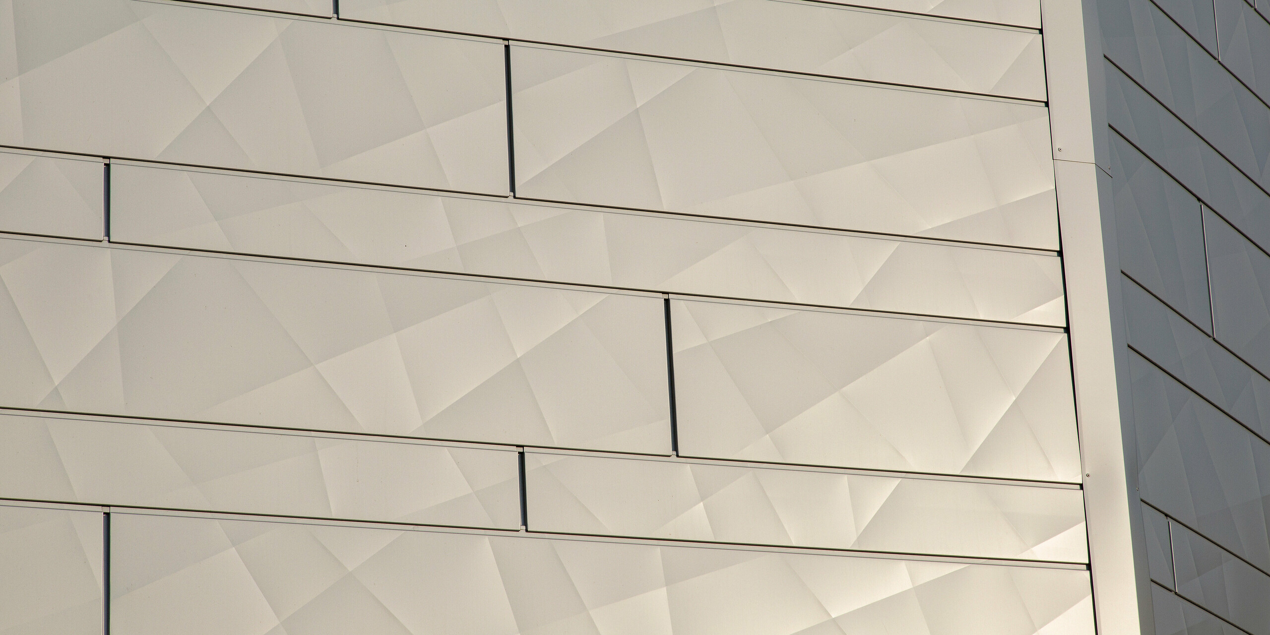 Detailansicht Gebäudekante mit schimmernden PREFA Siding.X Fassadenpaneelen in Silbermetallic am Optik- und Akustik-Shop AFFLELOU in Auray, Frankreich