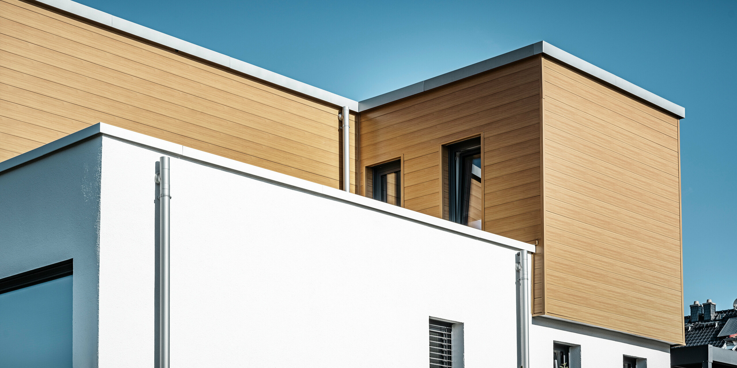 Seitliche Perspektive auf ein Einfamilienhaus in Usingen, Deutschland. Das Haus wurde großflächig mit PREFA Sidings aus Aluminium in der Farbe Eiche natur verkleidet. 