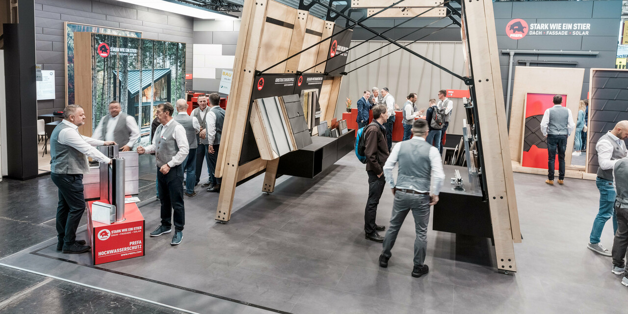 Belebter PREFA Messestand mit Messewänden mit den PREFA Aluminium Dachprodukten und Fassadenprodukten.