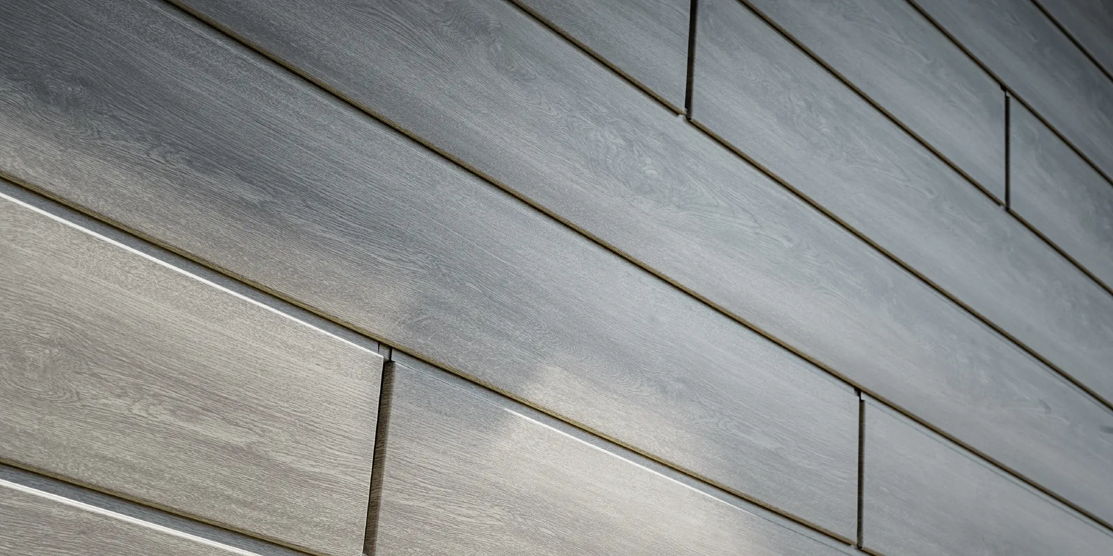Nahaufnahme der PREFA Sidings Aluminium Fassade, die Alu-Paneele wurden horizontal verlegt und in Holzoptik - Eiche beige grau