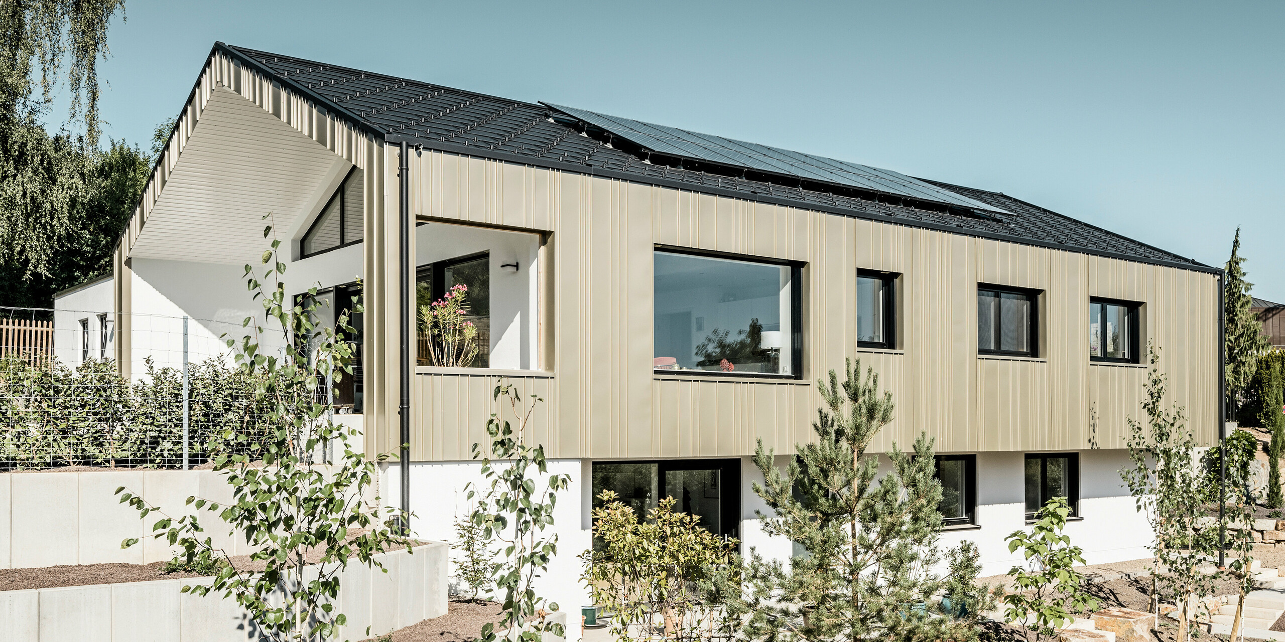 Ein Neubau in Bad Münstereifel wurde eingedeckt mit der PREFA Dachplatte R.16 in anthrazit. Auf dem Dach befindet sich eine Photovoltaik-Anlage. Die Winkelfalzfassade besteht aus Falzonal in lichtbronze.