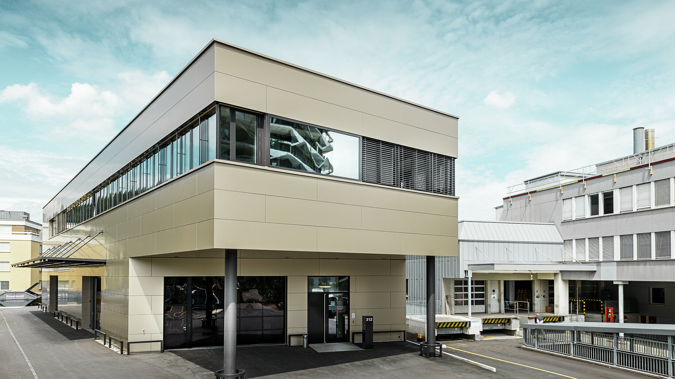 Moderner Zubau mit Werkstatt und Büro von Guggisberg Dachtechnik in Wabern (Schweiz). Die Gesamtansicht des Bürogebäudes betont die stilvolle PREFA Aluminiumfassade in Bronze. Die horizontal ausgerichtete Linienführung und das Flachdach unterstreichen die zeitgemäße Formensprache und die exklusive Materialwahl.