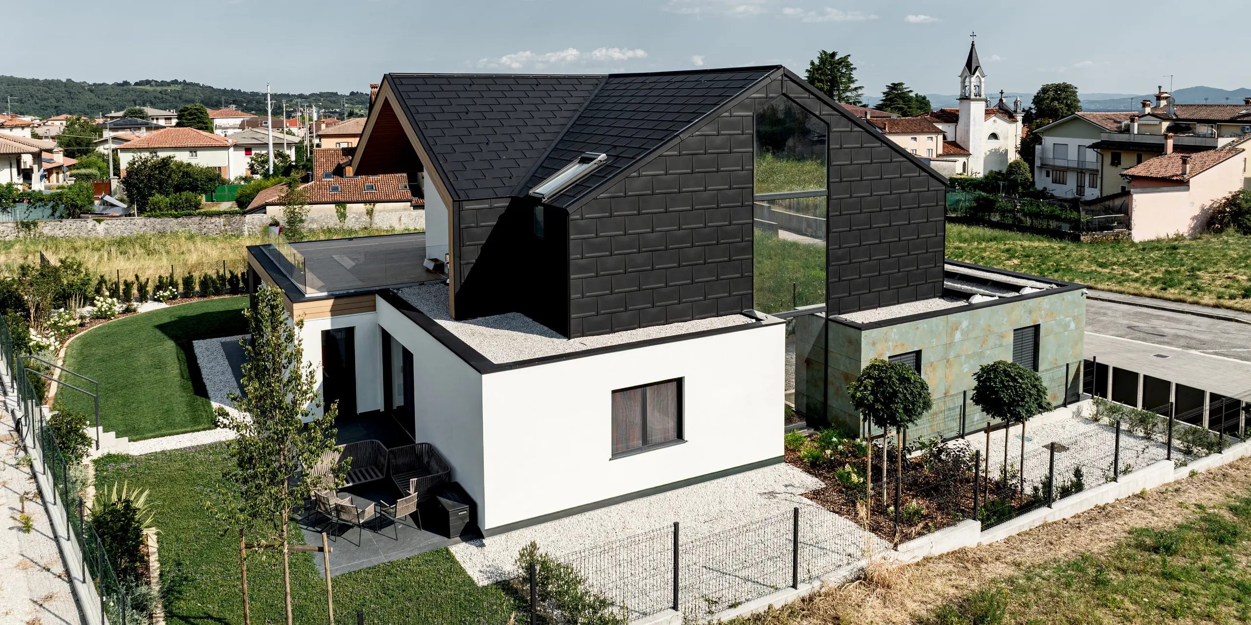 Modernes Einfamilienhaus in Vicenza mit markanter schwarzer PREFA Dach- und Fassadenbekleidung. Die PREFA Dachplatte R.16 in P.10 Schwarz verleiht dem Gebäude eine elegante, einheitliche Optik und schützt zuverlässig vor Witterung. Die langlebigen Aluminiumprodukte setzen einen architektonischen Akzent in der mediterranen Umgebung und verbinden Design mit Beständigkeit.