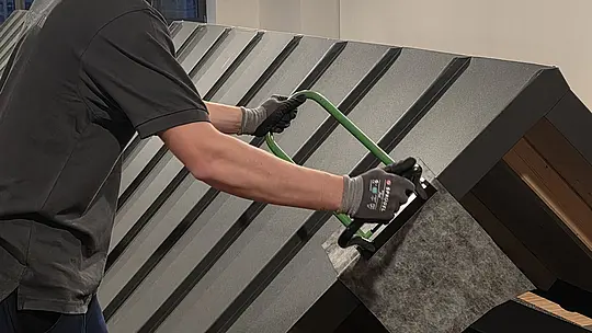 Ein Teilnehmer der Deutschen Meisterschaft im Klempnerhandwerk verwendet einen Winkelfalzschließer, um eine Dachplatte präzise zu bearbeiten.