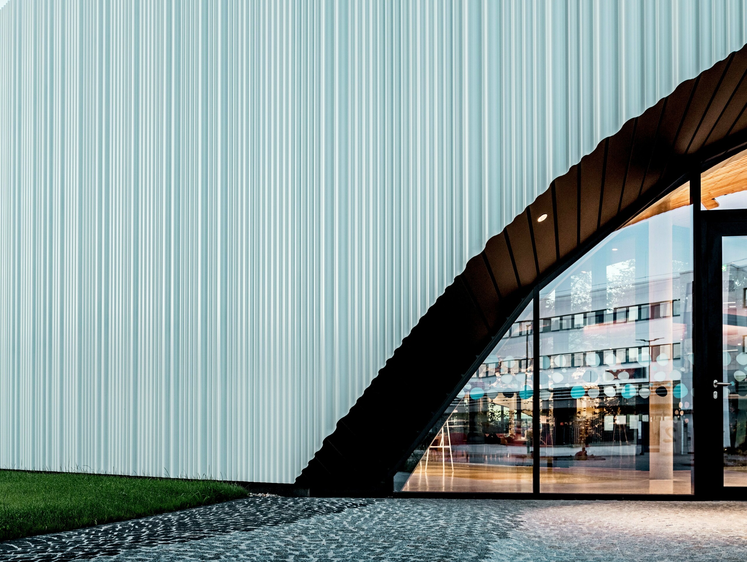 Eine spektakuläre Fassadengestaltung mit PREFA Strangpressprofil Welle aus hochwertigem Aluminium ziert das Firmengebäude von LKW Walter in Wien. Die sanft geschwungene, vertikal verlaufende Profilstruktur erzeugt ein elegantes Wellenbild, das faszinierende Lichtspiele erzeugt. Während das moderne Gebäude mit einer klaren Formsprache überzeugt, schafft der geschwungene Fassadenausschnitt einen markanten architektonischen Kontrast. Die langlebigen und korrosionsbeständigen Aluminiumprofile mit verdeckter Befestigung sorgen für eine hochwertige und wartungsfreie Außenhaut.