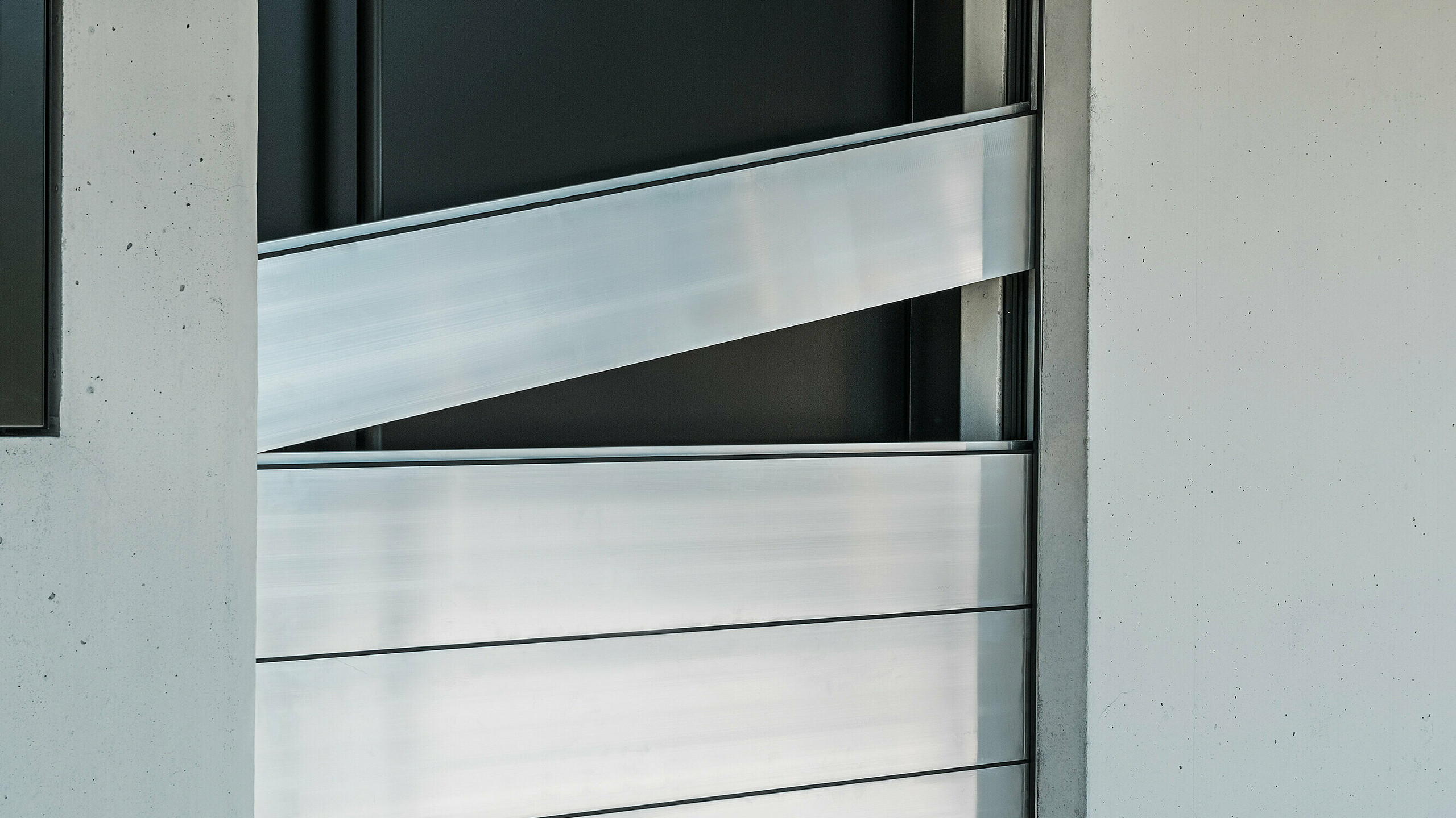 Detailansicht der Verbindungselemente des PREFA Hochwasserschutzsystems. Die innovative Technik sorgt für eine sichere Abdichtung der Haustür und schützt effektiv vor Hochwasser. Die Dammbalken werden schräg eingeschoben, wie am oberen Element deutlich zu erkennen ist.