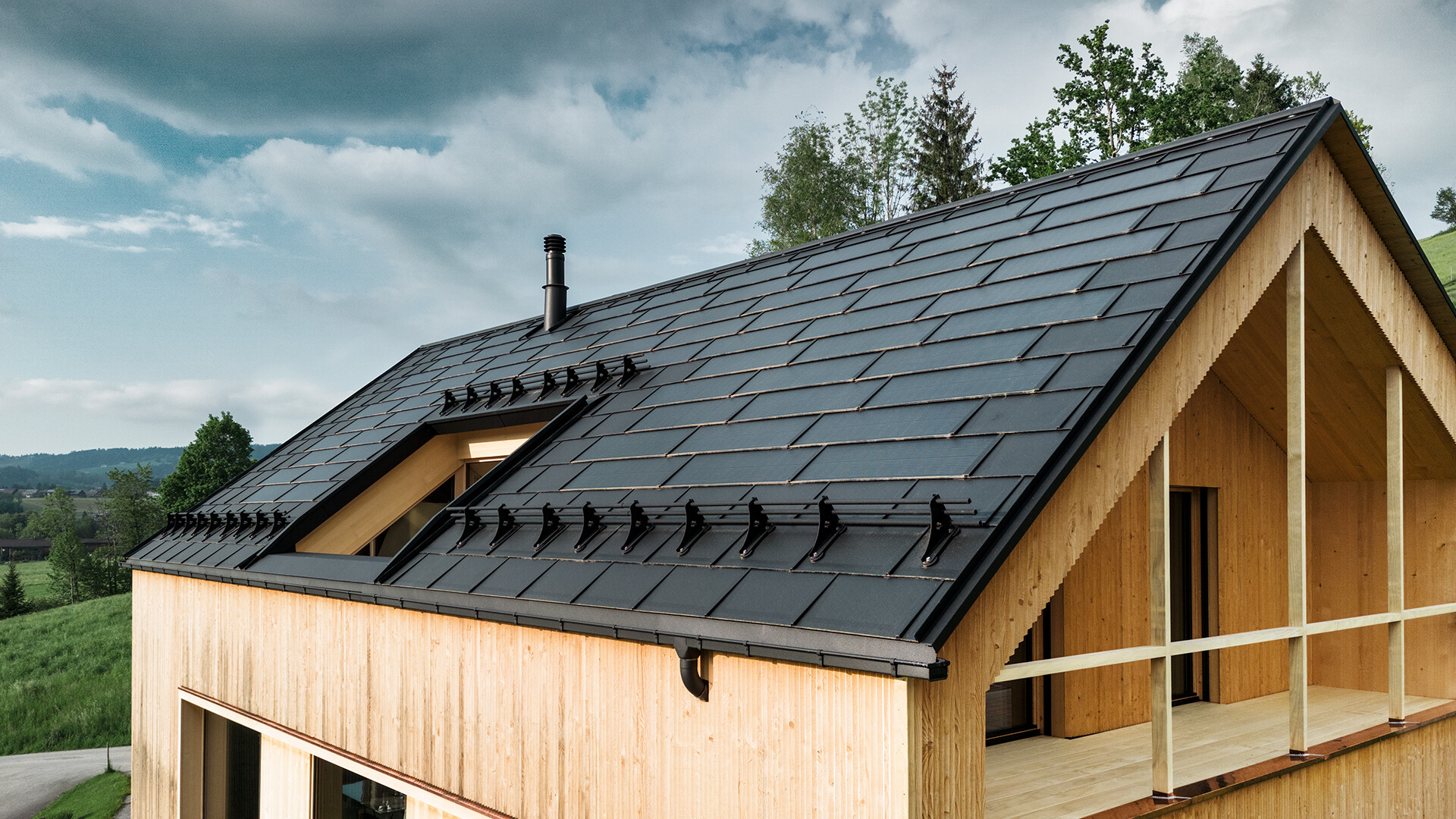 PREFA Solardachplatte in Schwarz auf einem Ökohaus in Egg, Österreich – langlebig, energieeffizient und ästhetisch ansprechend für moderne Architektur. Die innovative Solardachplatte vereint ein sturmsicheres Dach mit einer Photovoltaikanlage. Die integrierten PV-Module fügen sich harmonisch am Dach des Einfamilienhauses ein.