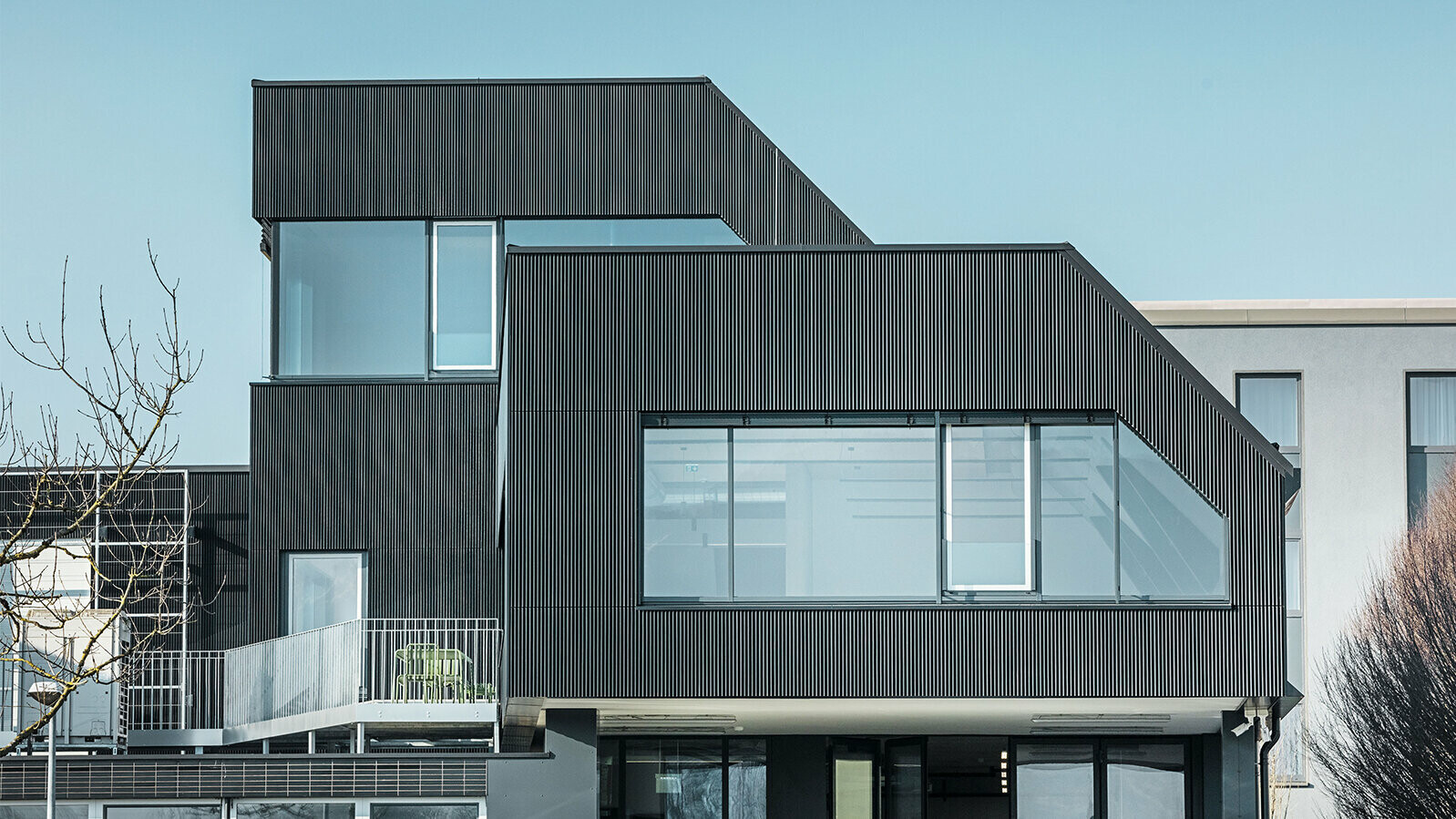 Seitliche Ansicht des Amann-Kaffeegebäudes an einem sonnigen Tag. Zum Schutz des Gebäudes wurde ein geriffeltes Profil in der Farbe Schwarz verwendet.