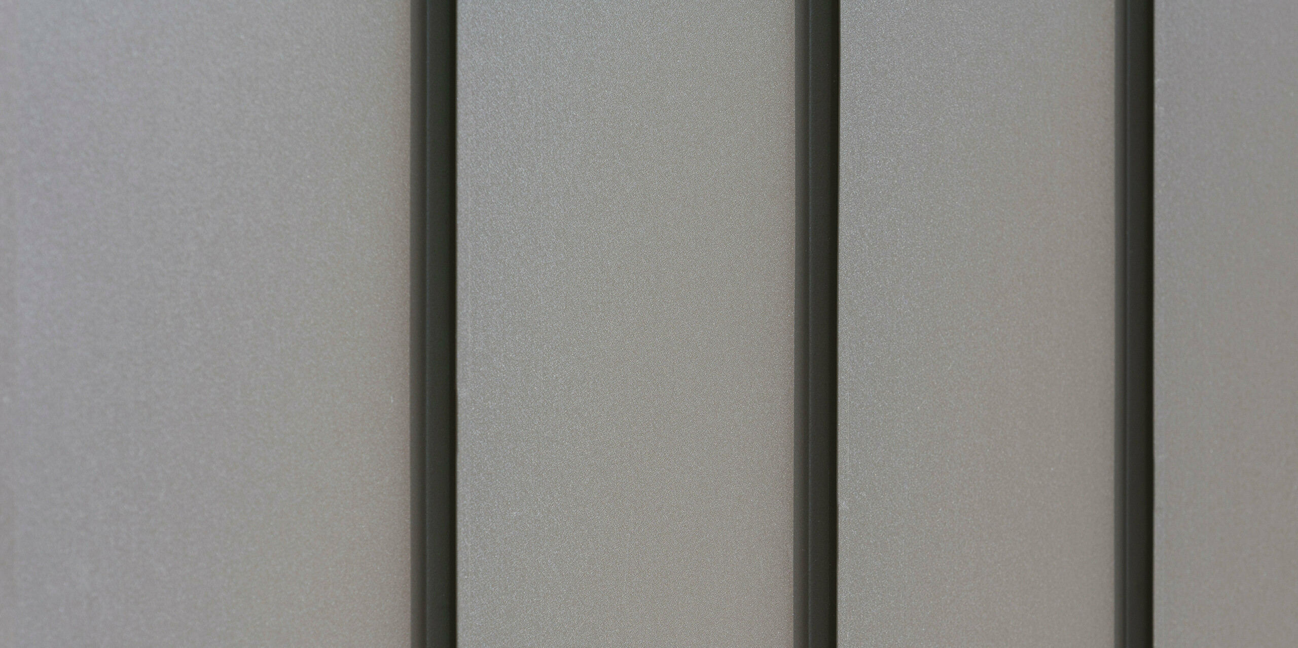 Nahaufnahme einer modernen Fassadenverkleidung aus Aluminium mit vertikalen Scharen, die für ein ästhetisch strukturiertes Muster sorgen. Das Aluminium kommt von der PREFA Aluminiumprodukte GmbH.