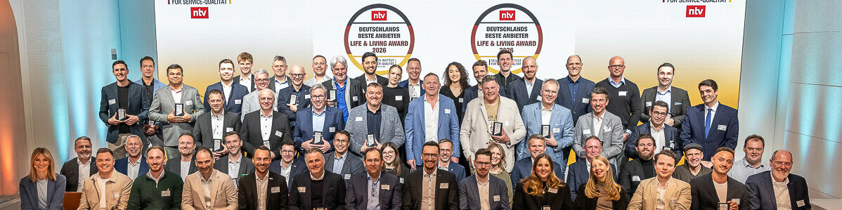 Gruppenfoto der Preisträgerinnen und Preisträger des Life & Living Award 2026 auf einer Bühne, alle mit ihren Auszeichnungen in den Händen.