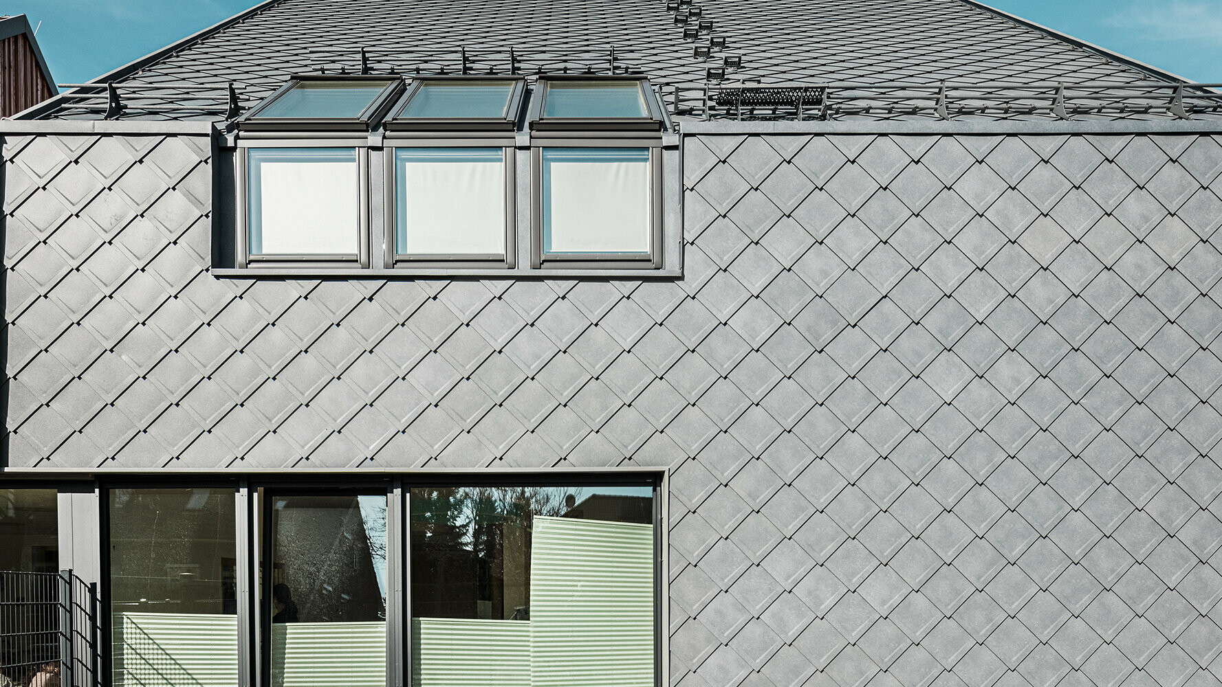 Moderne Architektur mit PREFA Fassadenbekleidung. Die PREFA Wandrauten 29x29 in der Farbe P.10 Steingrau verleihen dem Gebäude eine markante und auffällige Optik.