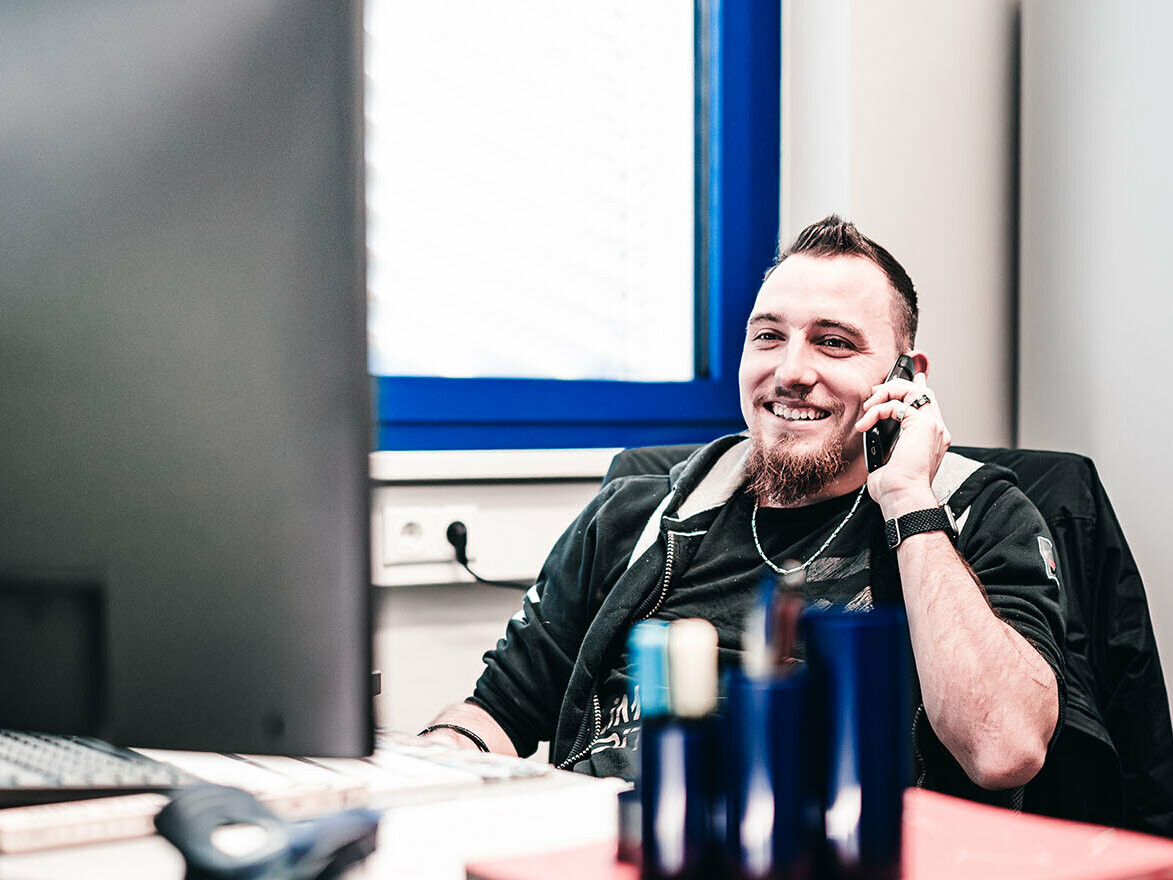 PREFA Mitarbeiter Pascal Luck telefoniert mit einem Kunden, der technische Beratung zu seinem Solardach benötigt.