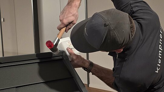 Ein Teilnehmer der Deutschen Meisterschaft im Klempnerhandwerk schlägt mit einem Hammer auf das Metall, um die Teile für eine Dachdeckung passgenau zu verbinden. Der Wettbewerb verlangt höchste Handwerkskunst und technisches Geschick.