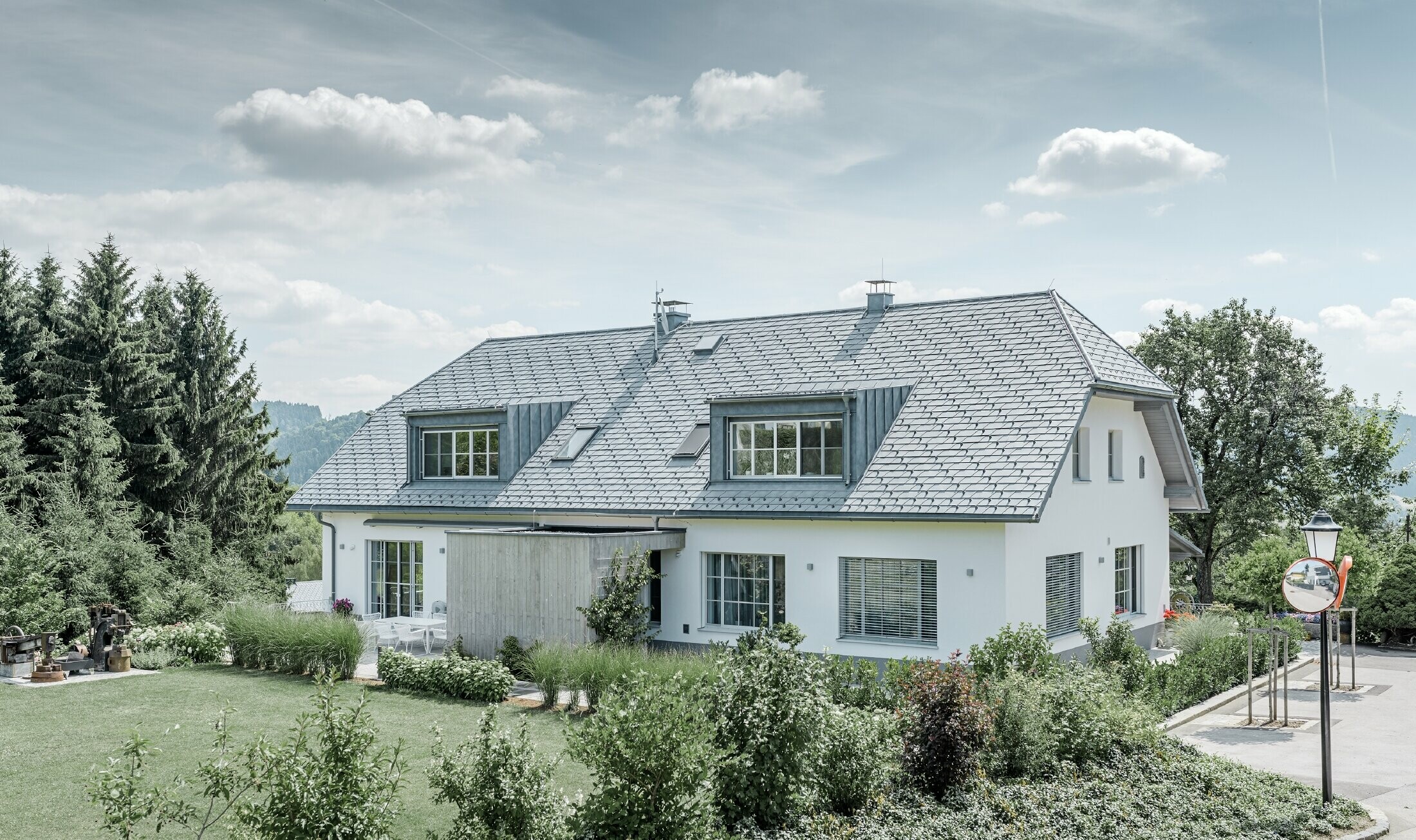 Gaube des neu sanierten Einfamilienhauses mit der PREFA Dachschindel in Steingrau. Die Gaube ist mit Prefalz (Stehfalz) verkleidet.