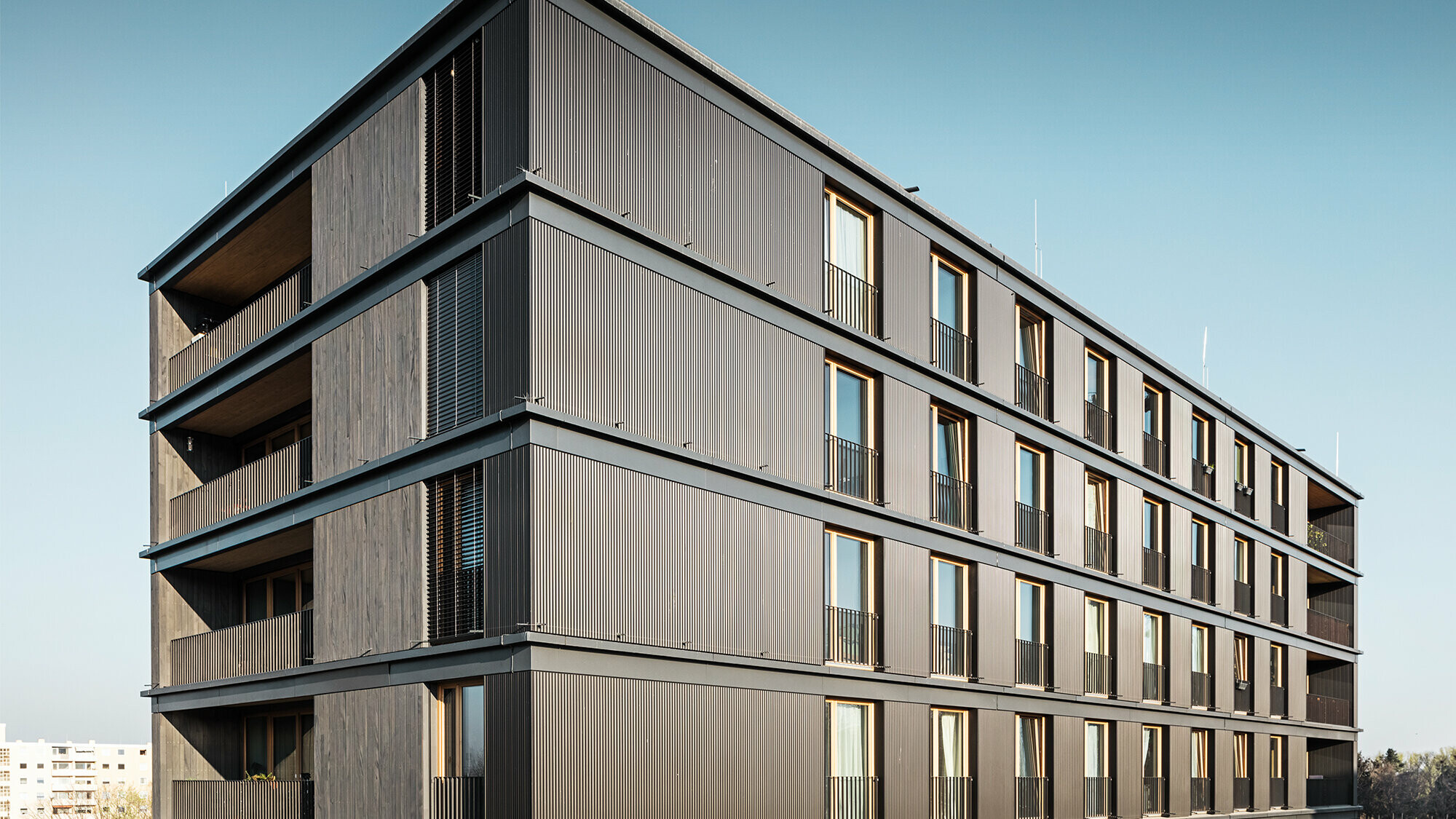 Das Wohn- und Geschäftshaus aus der Seitenperspektive: Die Profilwelle von PREFA und die Holzfassade sind kaum voneinander zu unterscheiden.