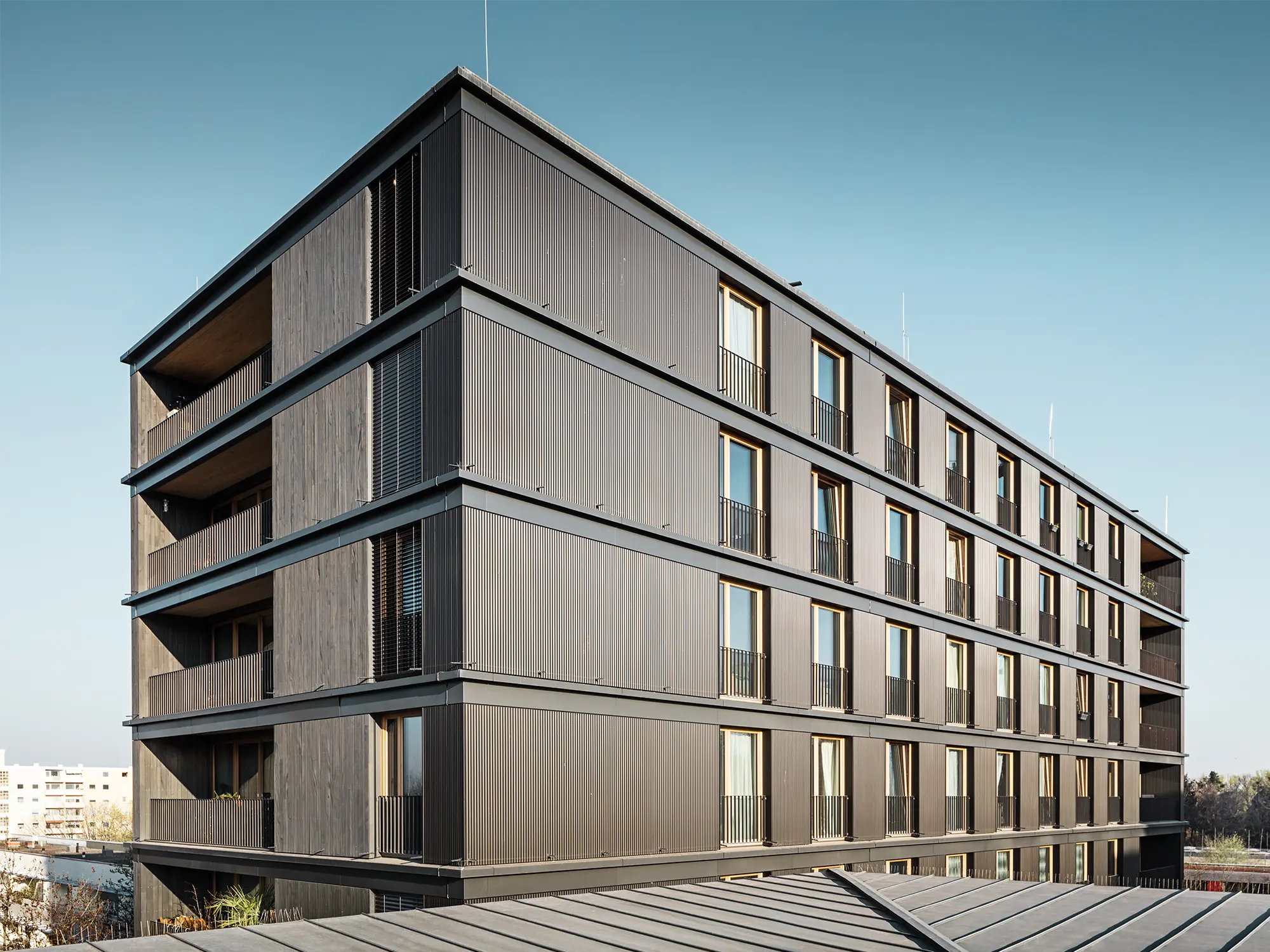 Das Wohn- und Geschäftshaus aus der Seitenperspektive: Die Strangpress-Welle von PREFA und die Holzfassade sind kaum voneinander zu unterscheiden.