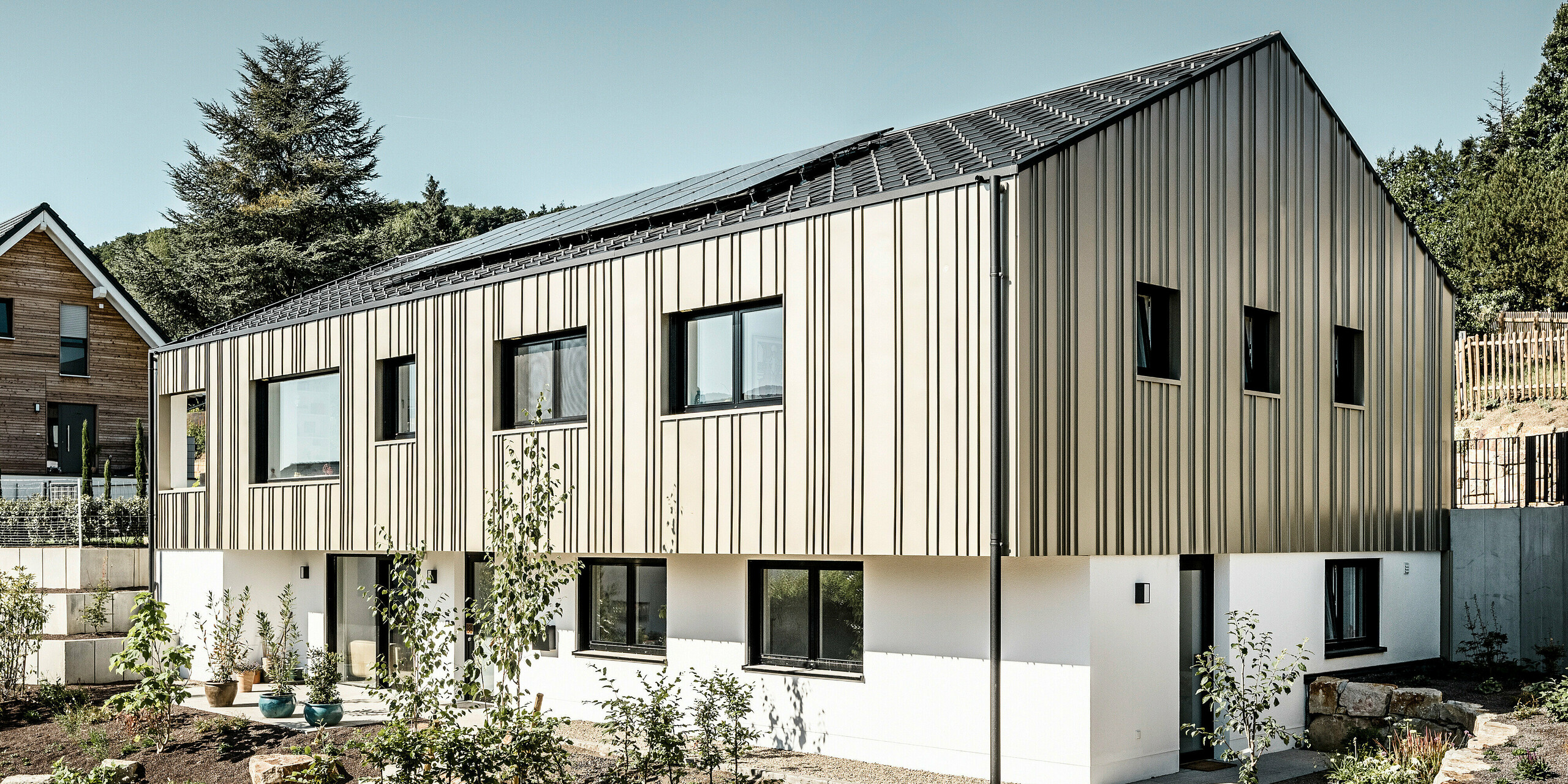 Ein Neubau in Bad Münstereifel wurde eingedeckt mit der PREFA Dachplatte R.16 in anthrazit. Auf dem Dach befindet sich eine Photovoltaik-Anlage. Die Winkelfalzfassade besteht aus Falzonal in lichtbronze.