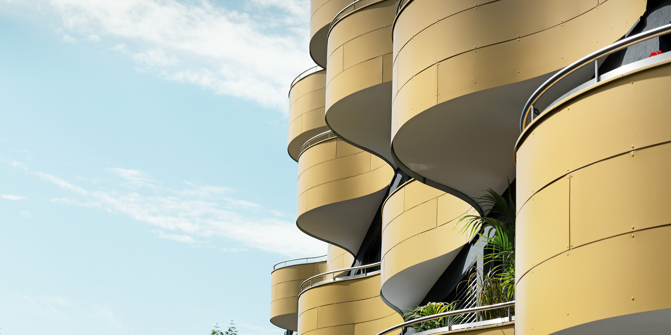 Nahaufnahme der wellenförmigen Balkone eines Wohnhauses in Graz. Die runde Fassadengestaltung wurde mit goldfarbenen Aluminium Cerbundplatten verkleidet.