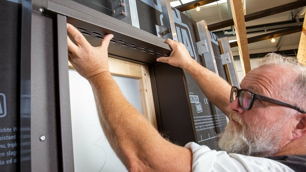 Detailaufnahme eines Fenster, bei dem der PREFA Techniker das Sturzblech einbaut und am oberen Fensterrand befestigt. 