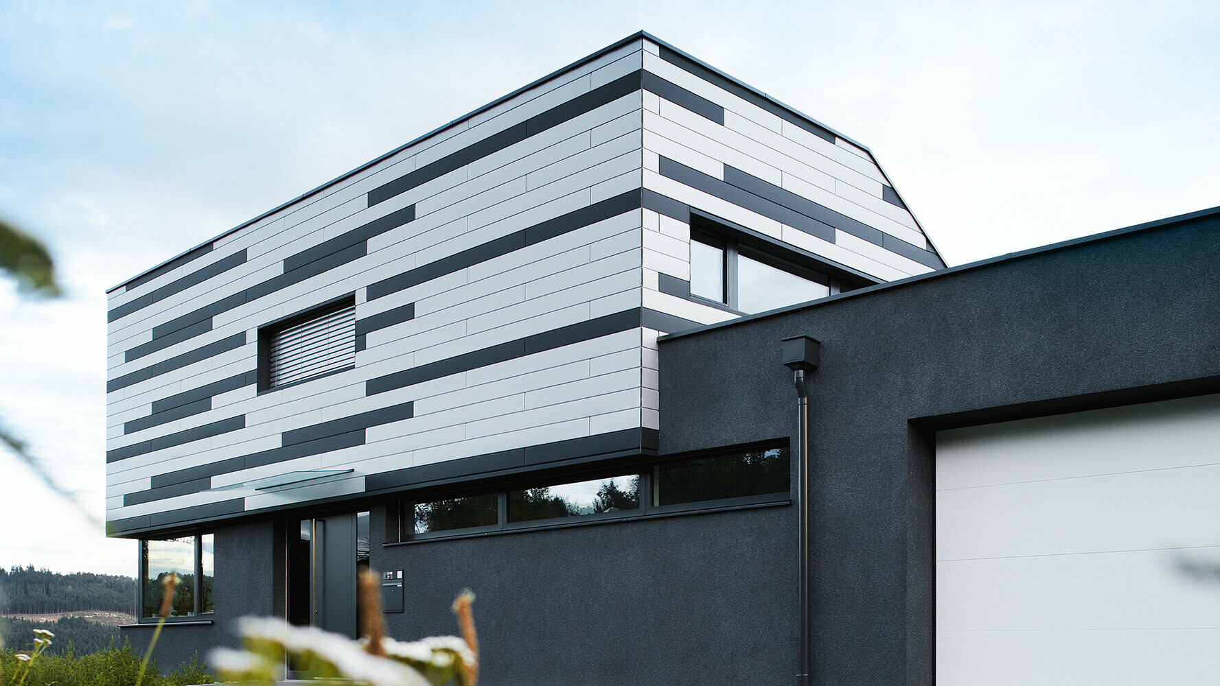Modernes Einfamilienhaus mit kreativer Fassadengestaltung; Die PREFA Sidings wurden in Silber und Anthrazit matt gemischt verlegt.
