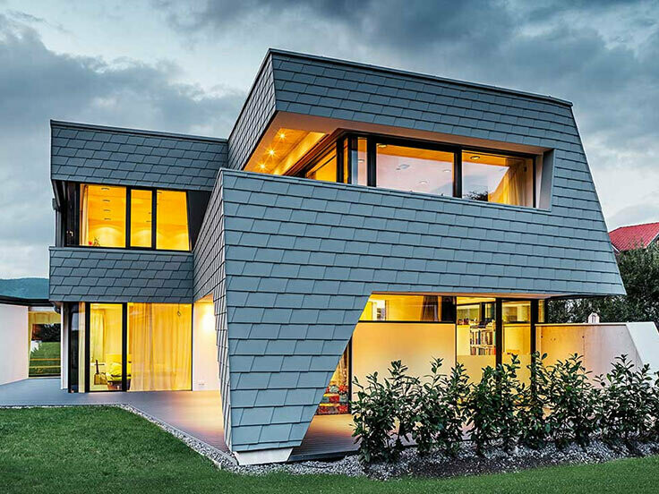 Aufnahme eines modernen Einfamilienhauses bei Abenddämmerung; Die Fassade ist mit der Wandschindel in Grau.